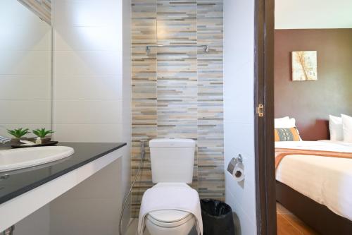 a bathroom with a toilet and a sink and a bed at Baan Kieng Tawan in Khong Chiam