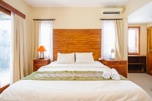 a bedroom with a large white bed with two windows at Dinar Hills Ungasan in Nusa Dua