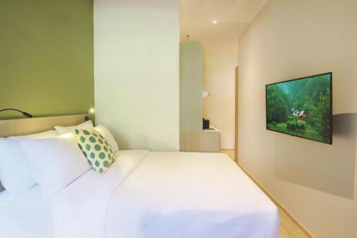 a bedroom with a white bed and a tv on the wall at Coliwoo 298 River Valley - CoLiving in Singapore