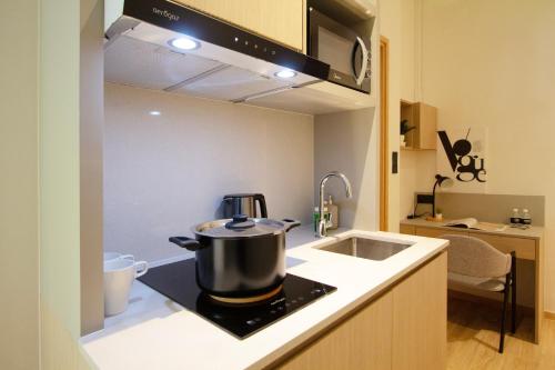 a pot on a stove in a small kitchen at Coliwoo 298 River Valley - CoLiving in Singapore