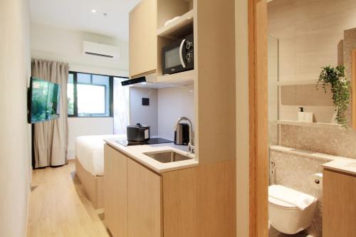 a kitchen with a sink and a toilet in a room at Coliwoo 298 River Valley - CoLiving in Singapore