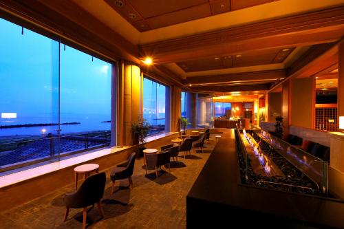 a restaurant with a bar with a view of the ocean at Ooedo Onsen Monogatari Premium Shiomiso in Murakami
