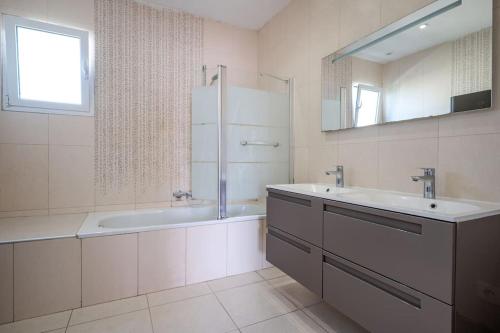 La salle de bains blanche est pourvue d'une baignoire, d'un lavabo et d'une baignoire. dans l'établissement Villa moderne avec Piscine, proche mer, à Villeneuve-Loubet