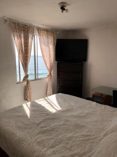 a bedroom with a large bed and a window at Recámara frente al mar, cama King, tv, wifi in Tijuana