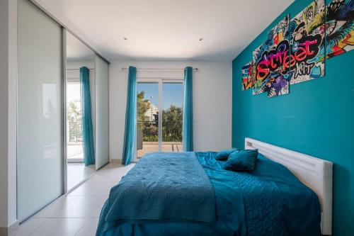 une chambre avec un lit avec un mur bleu dans l'établissement Villa moderne avec Piscine, proche mer, à Villeneuve-Loubet