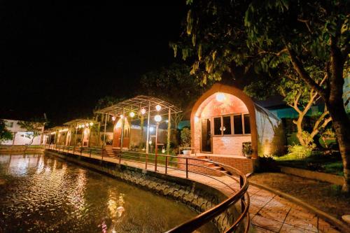 a group of buildings with lights on a river at night at Hoa Lu Garden Resort in Ninh Binh