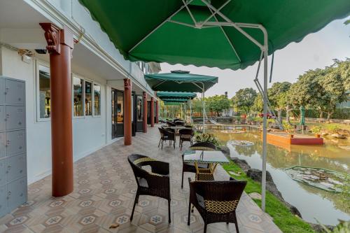 a patio with tables and chairs and a green umbrella at Hoa Lu Garden Resort in Ninh Binh