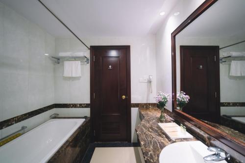 un bagno con vasca e un grande specchio di Saigon Dalat Hotel a Da Lat