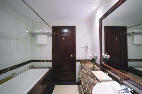 een badkamer met een bad en een grote spiegel bij Saigon Dalat Hotel in Da Lat