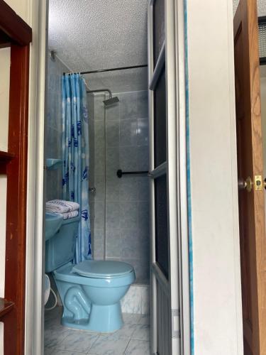a bathroom with a blue toilet and a shower at HOTEL GALES SOGAMOSO in Sogamoso