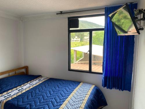 a bedroom with a bed and a window with a view at HOTEL GALES SOGAMOSO in Sogamoso