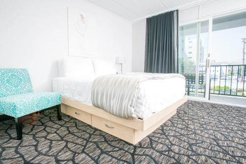 a bedroom with a bed and a chair and a window at Periwinkle Inn in Cape May