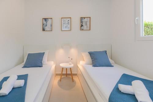 two beds in a white room with blue pillows at NEW!!! Luminose beach house in Pakoštane
