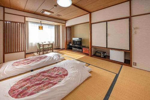 una camera con due letti e una tv di Hotel Shin Makomo a Itako