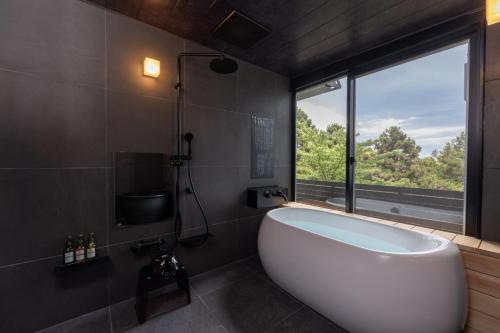 a bathroom with a large white tub and a window at ISHINOYA Atami in Atami