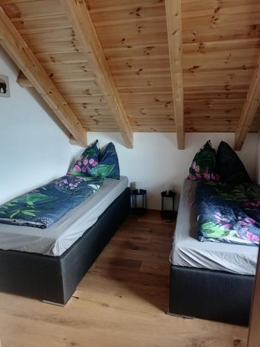 two beds in a room with wooden ceilings at Bergzauber View in Ramsau am Dachstein