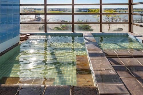 a swimming pool with a view of the water at Hotel Shin Makomo in Itako