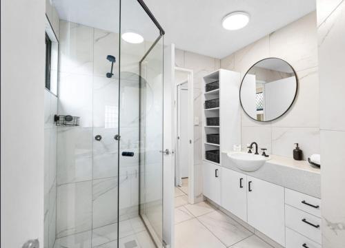 a white bathroom with a shower and a sink at Mooloolaba Beach Club Paradise 2 Bedroom Apartment in Mooloolaba