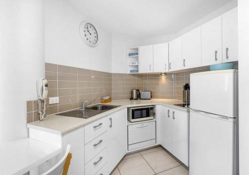 a kitchen with white cabinets and a white refrigerator at Mooloolaba Beach Club Paradise 2 Bedroom Apartment in Mooloolaba