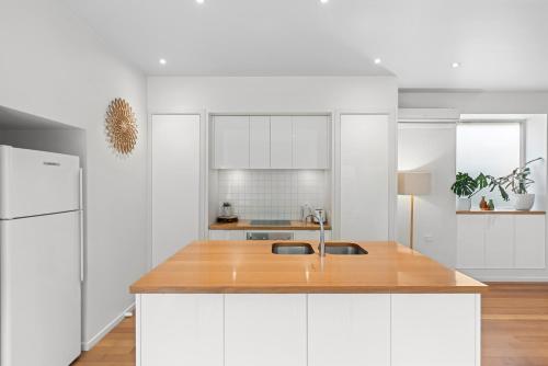a kitchen with white cabinets and a wooden counter top at The White House in Geelong