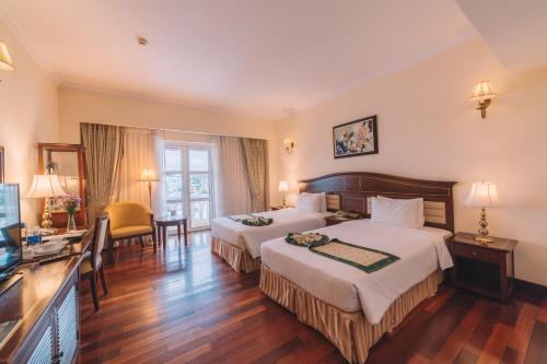 una camera d'albergo con due letti e una televisione di Saigon Dalat Hotel a Da Lat
