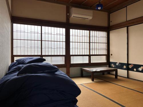 a room with a bed and a bench and windows at Stay Do in Oshima