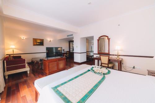 a bedroom with a bed and a flat screen tv at Saigon Dalat Hotel in Da Lat