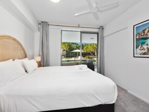 um quarto com uma cama branca e uma janela em Drift South Apartments by Kingscliff Accommodation em Casuarina