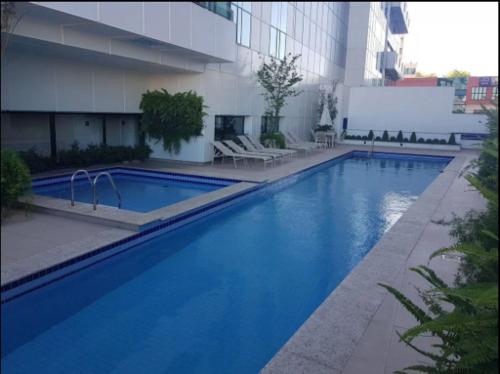 uma grande piscina azul em frente a um edifício em Conjunto Estudio e Duplex Selenita em Barueri