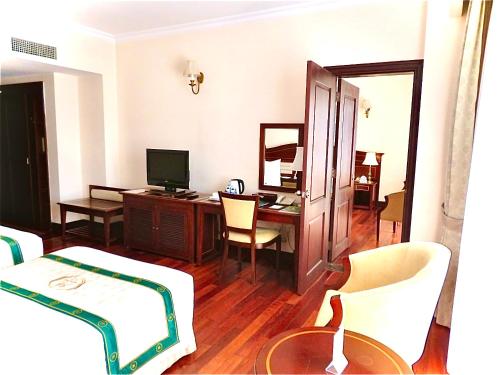 a room with a desk with a computer and a bedroom at Saigon Dalat Hotel in Da Lat