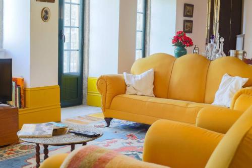 a living room with a yellow couch and a table at The Big House-grand comfort at Serra da Estrella in Gouveia