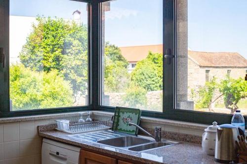 a kitchen with a sink and two large windows at The Big House-grand comfort at Serra da Estrella in Gouveia
