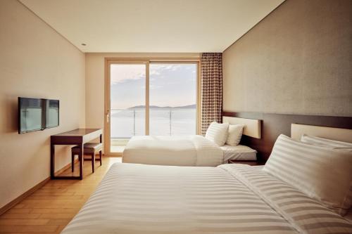 a hotel room with two beds and a window at Sono Calm Geoje in Geoje 