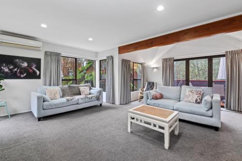 a living room with two couches and a coffee table at Bushland Retreat - Rotorua Holiday Home in Koutu