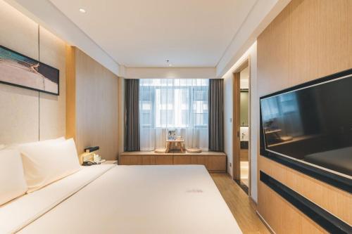 a bedroom with a bed and a flat screen tv at Atour Hotel (Wuxi Berkesy) in Wuxi