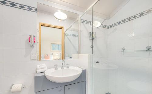Baño blanco con lavabo y espejo en Lhotsky 3 Bedroom and loft with fireplace mountain views and 2 car spaces, en Thredbo