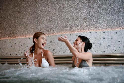 two women are playing in a bathtub with water at New World Hoiana Beach Resort in Hoi An