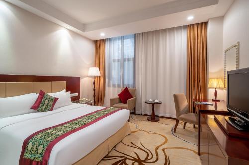 a hotel room with a bed and a television at Grand Metropark Hotel Shandong in Jinan