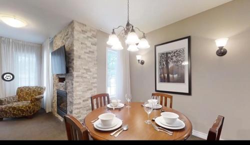 une salle à manger avec une table en bois et des chaises ainsi qu'une chambre avec une cheminée dans l'établissement Home Away From Home in Horse Shoe Valley, à Oro-Medonte