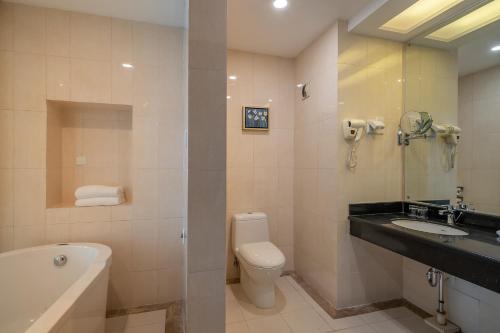 uma casa de banho com um lavatório, um WC e uma banheira em Grand Metropark Hotel Shandong em Jinan