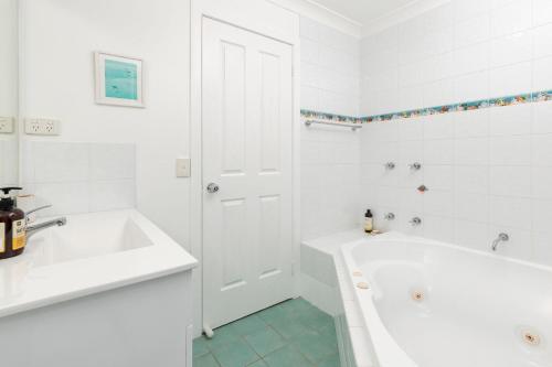 a white bathroom with a tub and a sink at Spinnaker 1 in Boomerang Beach