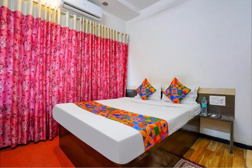 a bedroom with a bed and a red curtain at FabHotel Sai Chatra in Nashik