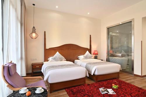 um quarto de hotel com duas camas e uma cadeira em Guilin Crystal Crescent Moon Hotel em Guilin