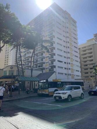 a white car parked in a parking lot with a bus at Waikiki Condo 2 Bedrooms 2 Bathrooms with 1 free parking space in Honolulu