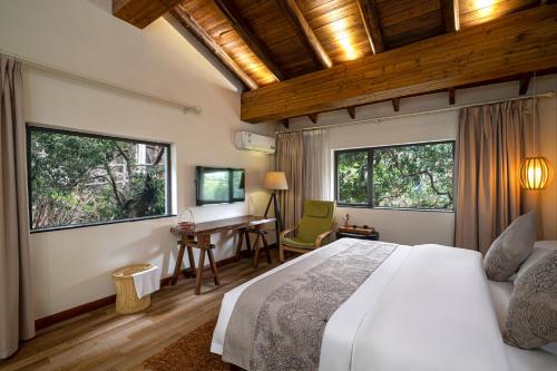 ein Schlafzimmer mit einem Bett und einem Schreibtisch und zwei Fenstern in der Unterkunft Guilin Crystal Crescent Moon Hotel in Guilin
