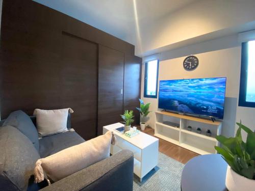 ein Wohnzimmer mit einem Sofa und einem Flachbild-TV in der Unterkunft Air Residences Makati - fully furnished condo with skyline views! in Manila