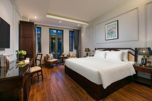 a bedroom with a large white bed and a desk at Salute Premium Hotel & Spa in Hanoi