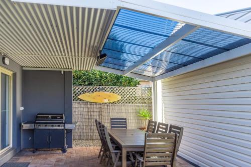a patio with a table and a surfboard under a roof at Bright and Breezy in Sussex inlet