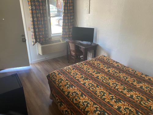 a bedroom with a bed and a desk with a television at Johnston's Motel in Garberville