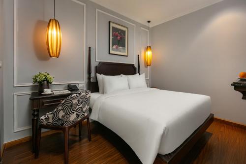 a bedroom with a large white bed and a chair at Salute Premium Hotel & Spa in Hanoi